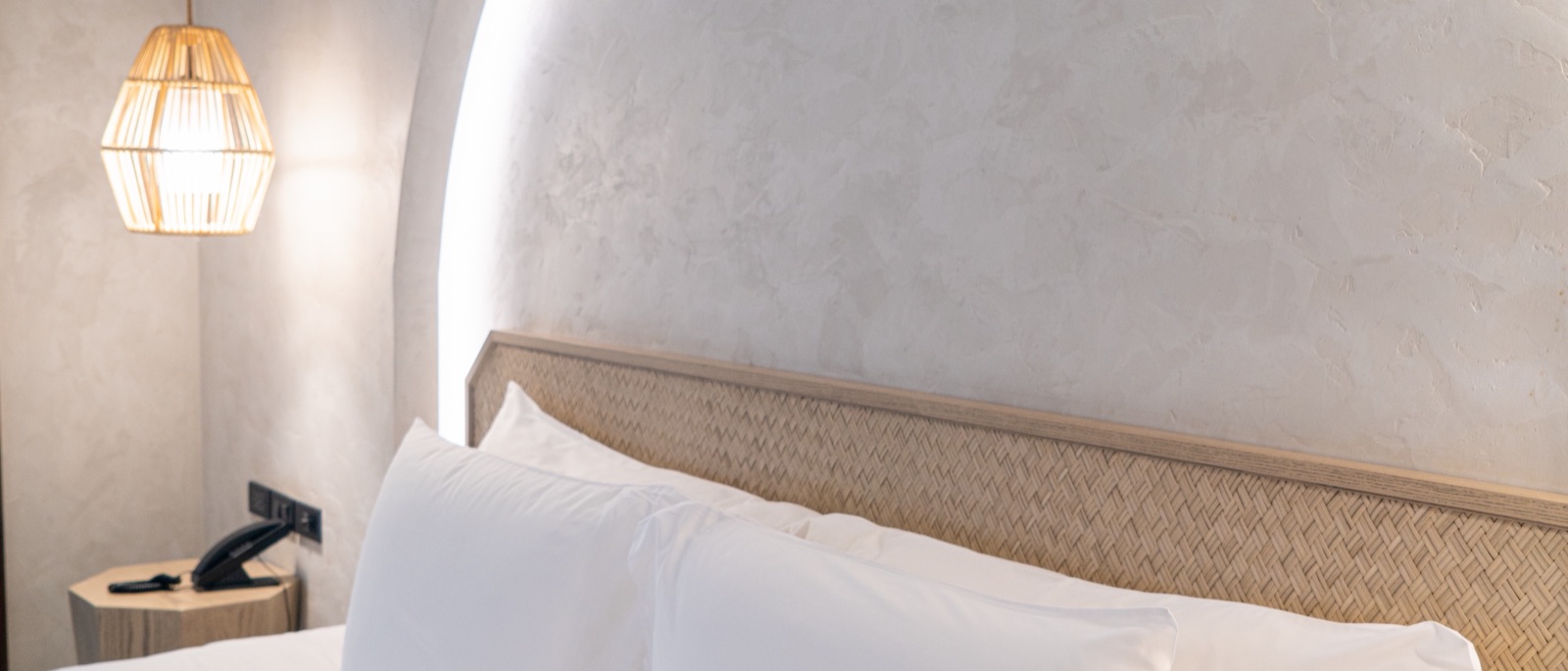 Chambre préparée : linge blanc repassé, tête de lit en fibre naturelle, lumière douce.